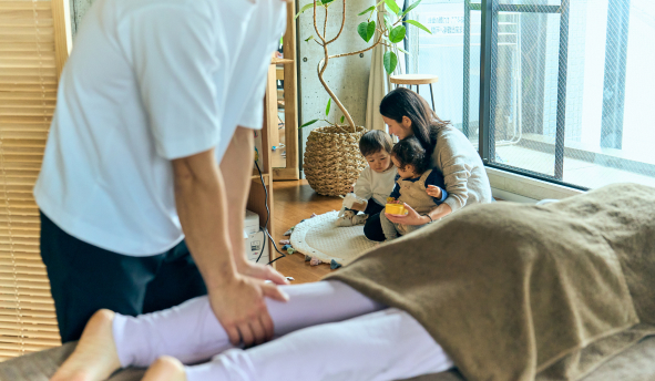 松本院長が女性に手技治療を行なっている中、お母さんが子供をあやしている。